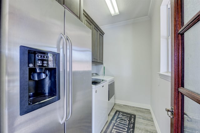 washroom with cabinet space, light wood finished floors, baseboards, ornamental molding, and washer and dryer