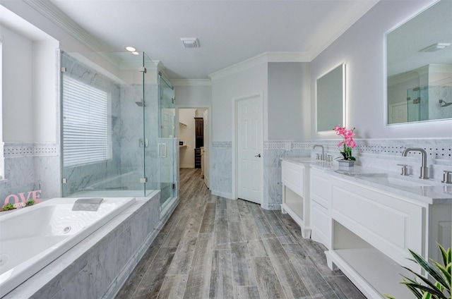 bathroom with wood finished floors, a sink, ornamental molding, a marble finish shower, and a bath