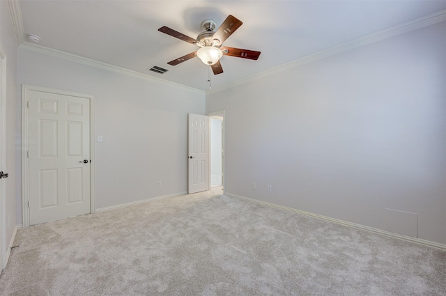 spare room featuring visible vents, baseboards, a ceiling fan, carpet, and crown molding