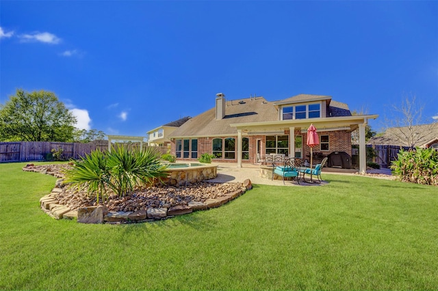 rear view of house with a patio, a fenced backyard, brick siding, a yard, and a chimney