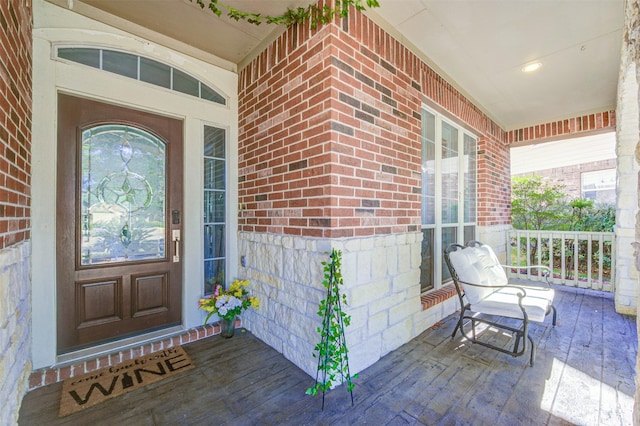 entrance to property featuring covered porch and brick siding