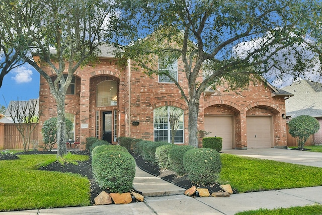 traditional-style home featuring driveway, brick siding, an attached garage, and fence