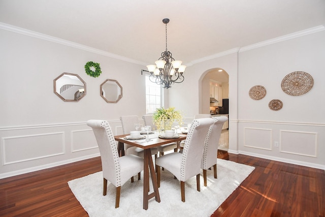 dining space with a chandelier, ornamental molding, wood finished floors, arched walkways, and a decorative wall