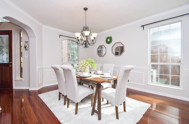 dining space with arched walkways, a notable chandelier, ornamental molding, and wood finished floors