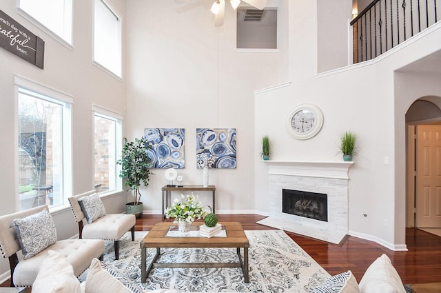 living area with ceiling fan, baseboards, wood finished floors, and a fireplace