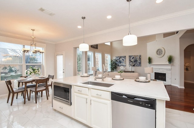 kitchen featuring visible vents, open floor plan, ornamental molding, stainless steel appliances, and a sink