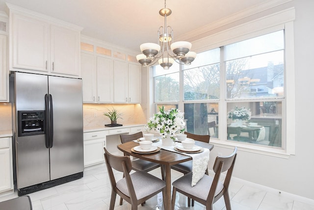 dining area featuring a notable chandelier, marble finish floor, crown molding, and baseboards