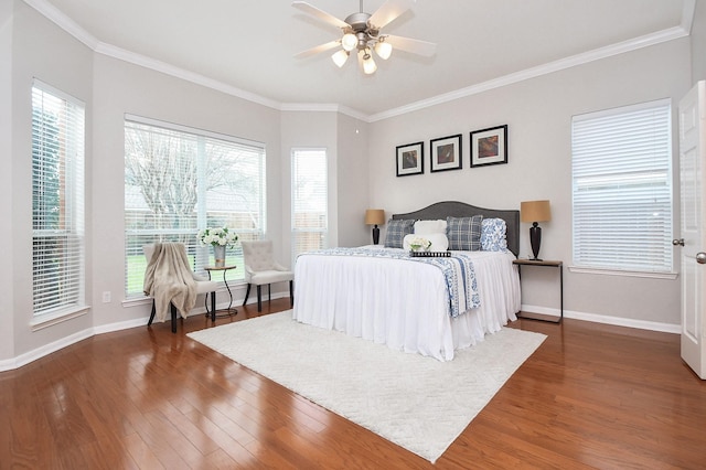 bedroom with baseboards, multiple windows, wood finished floors, and crown molding