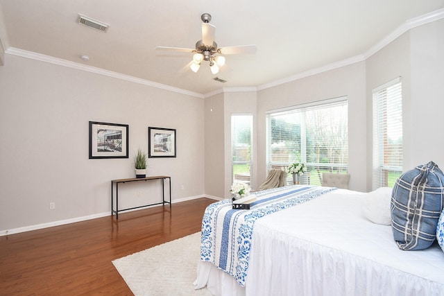 bedroom featuring baseboards, multiple windows, wood finished floors, and crown molding