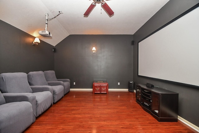 cinema room featuring baseboards, lofted ceiling, wood finished floors, and a ceiling fan