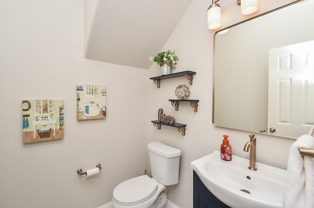 bathroom featuring baseboards, toilet, lofted ceiling, and vanity