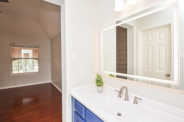 bathroom with baseboards, lofted ceiling, wood finished floors, and vanity