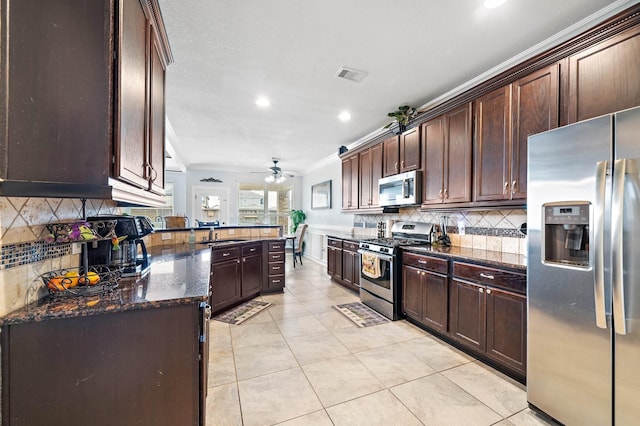 kitchen featuring visible vents, appliances with stainless steel finishes, ornamental molding, dark brown cabinetry, and dark stone counters