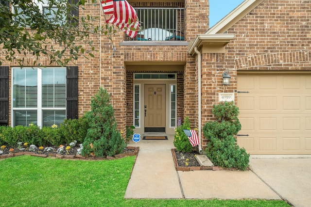 doorway to property with an attached garage, a balcony, and brick siding