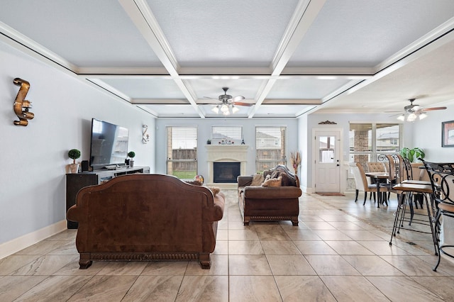 living area with baseboards, coffered ceiling, a ceiling fan, a glass covered fireplace, and beam ceiling