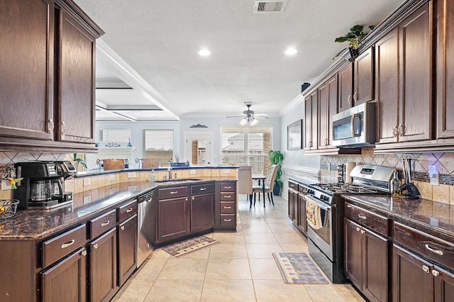 kitchen with visible vents, decorative backsplash, ornamental molding, a peninsula, and stainless steel appliances