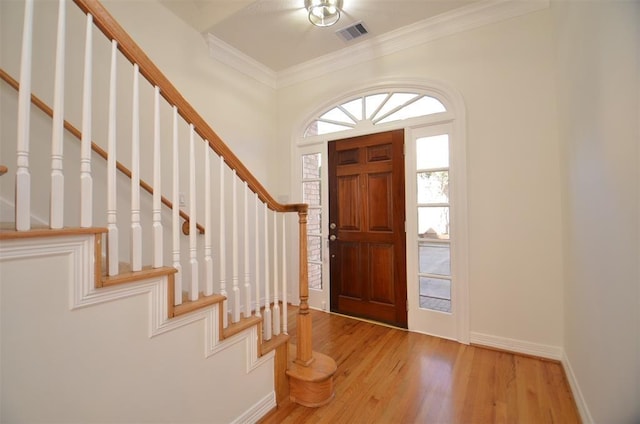 foyer featuring visible vents, ornamental molding, stairs, and light wood-style flooring