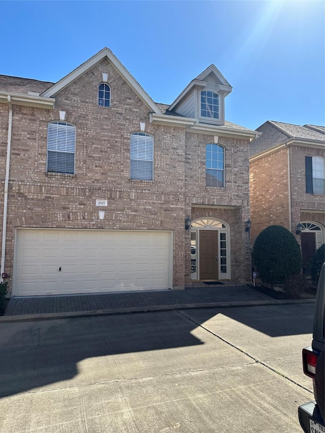 view of front of home featuring driveway, brick siding, and an attached garage