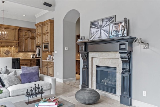 living area with a notable chandelier, arched walkways, crown molding, a premium fireplace, and baseboards