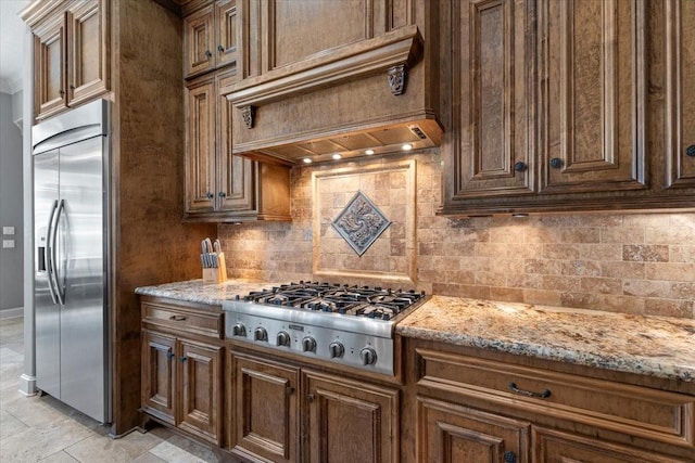 kitchen with decorative backsplash, custom range hood, light stone countertops, and stainless steel appliances