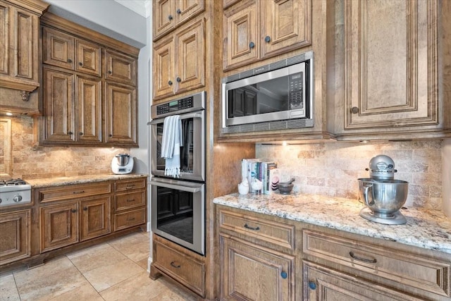 kitchen featuring brown cabinetry, backsplash, and appliances with stainless steel finishes