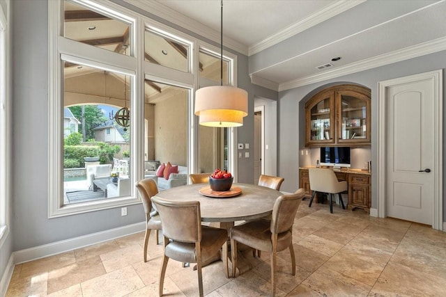 dining space featuring visible vents, stone finish flooring, built in desk, crown molding, and baseboards