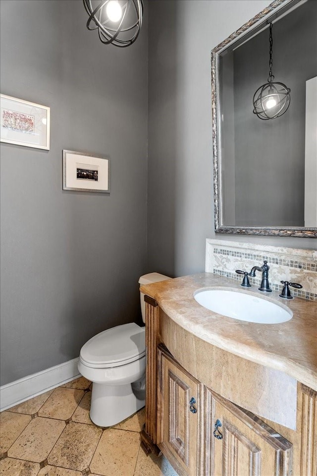 bathroom featuring baseboards, toilet, and vanity