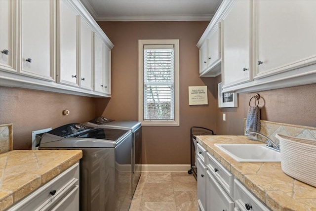 laundry area with a sink, cabinet space, crown molding, and washing machine and clothes dryer