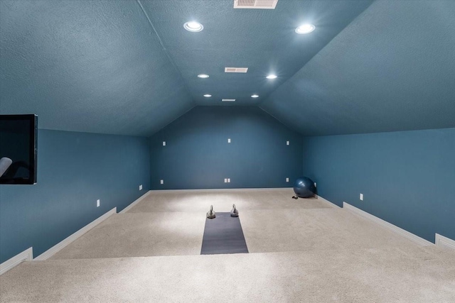 home theater featuring visible vents, baseboards, carpet, lofted ceiling, and a textured ceiling