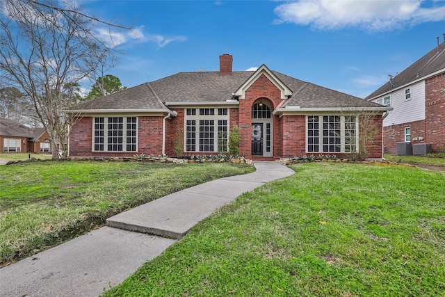 view of front of home with brick siding, a chimney, a front lawn, and a shingled roof