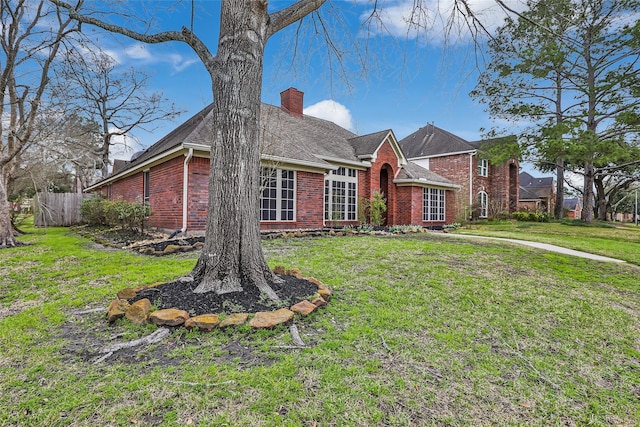 view of front of home with a front lawn, fence, brick siding, and a chimney