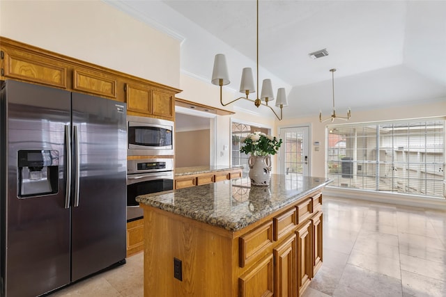 kitchen with visible vents, a kitchen island, appliances with stainless steel finishes, an inviting chandelier, and brown cabinetry