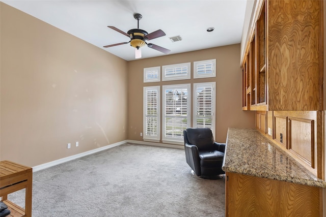 office featuring a ceiling fan, baseboards, visible vents, and light carpet