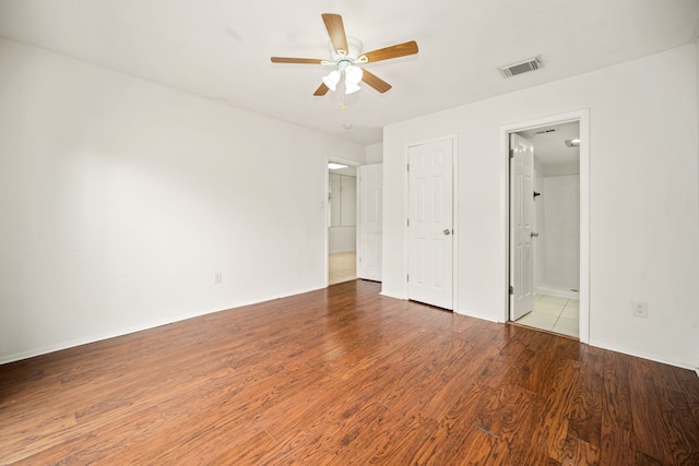 unfurnished bedroom featuring a ceiling fan, visible vents, connected bathroom, and wood finished floors