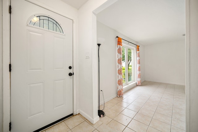 foyer entrance with light tile patterned floors and baseboards