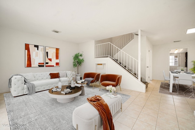 living room featuring light tile patterned floors, stairway, and visible vents