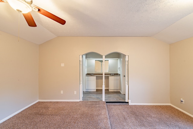 unfurnished bedroom with carpet, arched walkways, and vaulted ceiling