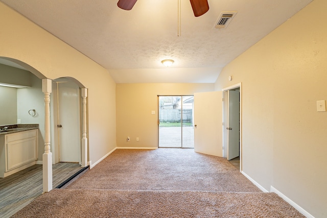 carpeted spare room featuring visible vents, a ceiling fan, vaulted ceiling, a sink, and baseboards