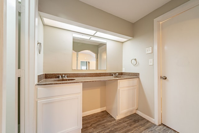 bathroom with a sink, double vanity, baseboards, and wood finished floors