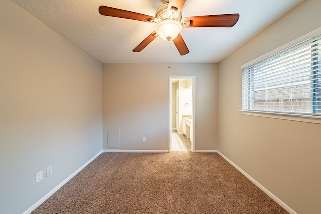 carpeted empty room with a ceiling fan and baseboards