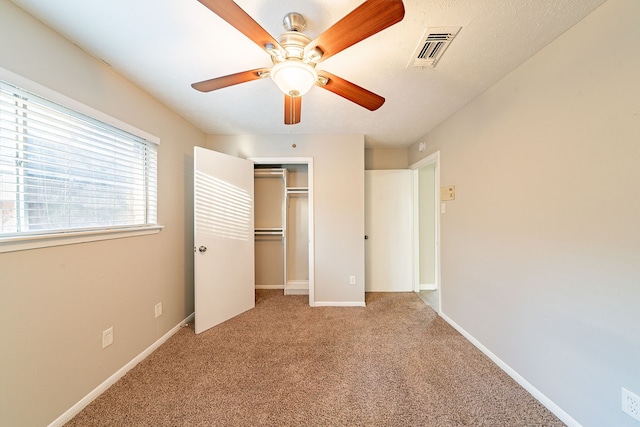 unfurnished bedroom featuring carpet, a closet, visible vents, ceiling fan, and baseboards