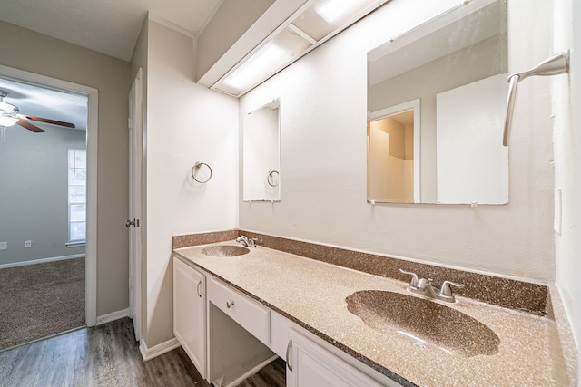 bathroom with double vanity, a sink, baseboards, and wood finished floors