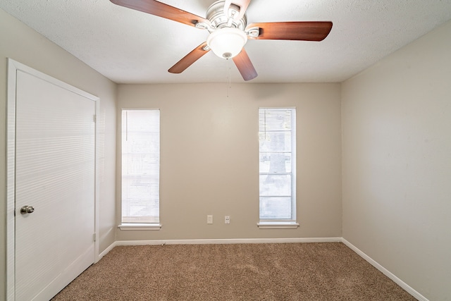 empty room with a textured ceiling, carpet floors, and baseboards