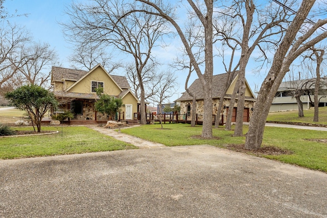 view of front of property with a porch, a front yard, stone siding, and roof with shingles