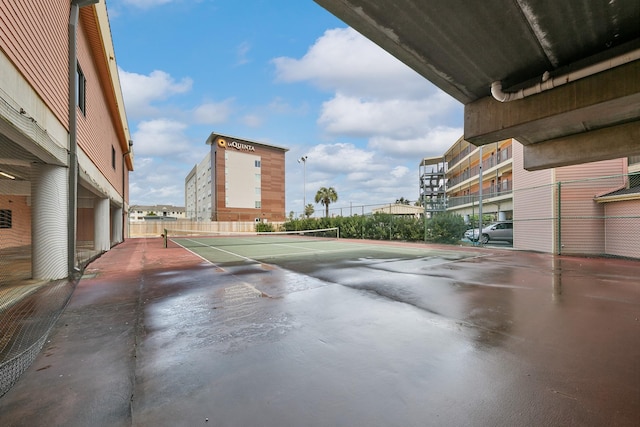 exterior space with a tennis court and fence