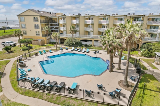 community pool featuring a water view, fence, and a patio