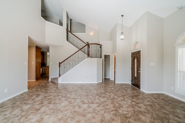 foyer entrance with high vaulted ceiling, stairway, and baseboards