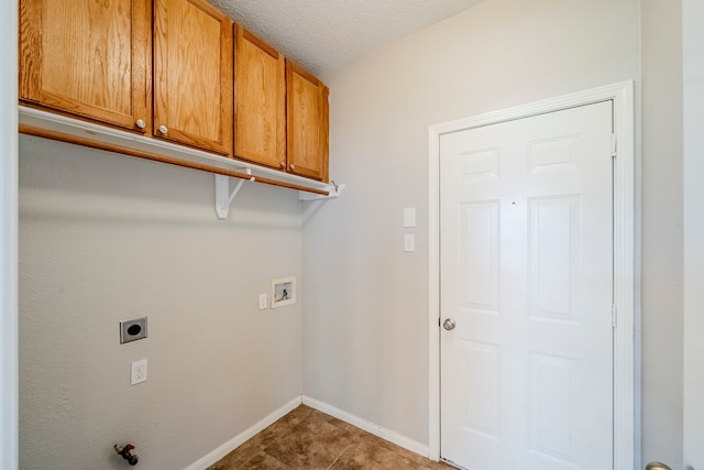 clothes washing area with a textured ceiling, hookup for a washing machine, hookup for an electric dryer, baseboards, and cabinet space