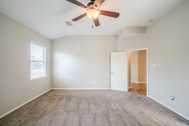 empty room featuring lofted ceiling, carpet, visible vents, and baseboards