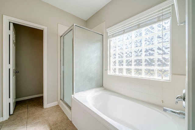 full bathroom featuring a garden tub, a stall shower, tile patterned flooring, and baseboards